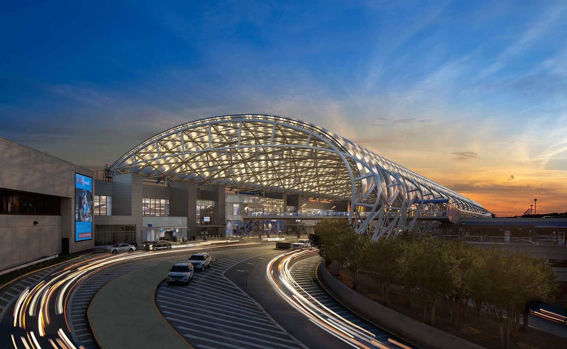 Hartsfield-Jackson Atlanta International Airport terminal canopy at dusk with traffic on the departures roadway